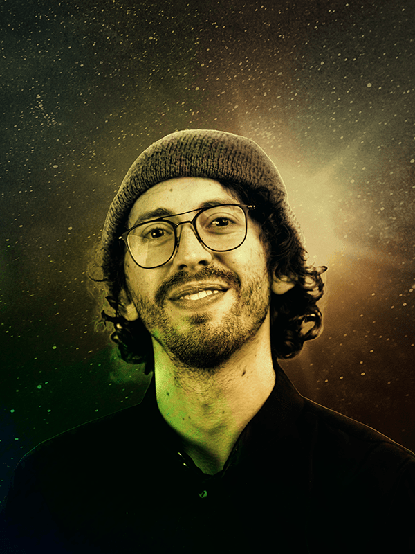 Carlos Arteaga. Carlos is in his mid-twenties, wearing a black button-up shirt, touque, square thin-framed glasses, with curly medium-shaggy hair and partial beard. Image is treated with a rainbow overlay to match the album artwork.